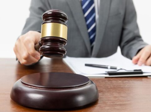 A closeup shot of a person with a gavel in hand and papers on the table